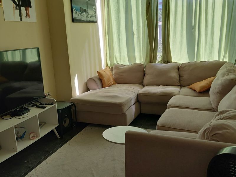 A comfortable living room featuring tiled flooring and a large window that allows for natural light.