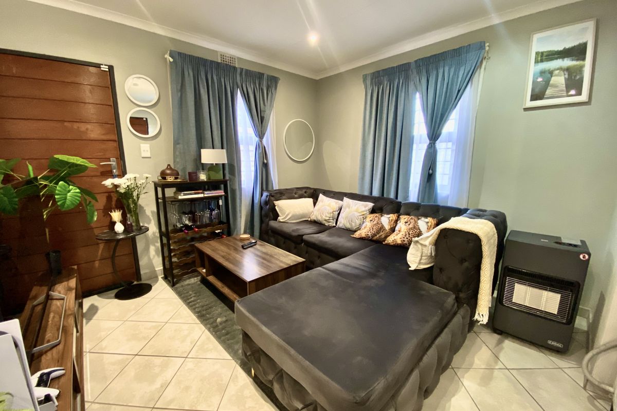 A comfortable living room featuring tiled flooring, recessed downlighting, and a timber entrance door, creating a functional and inviting space.