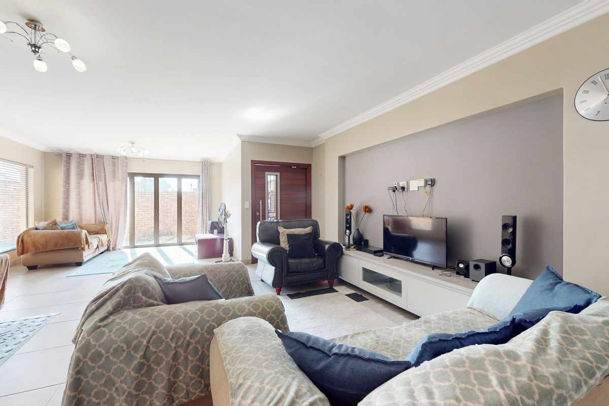 Spacious living room featuring tiled flooring, a recessed media wall, and large sliding glass doors providing access to the outdoor area.