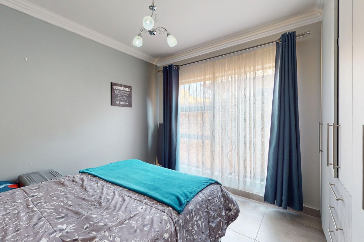 A well-maintained bedroom featuring built-in cupboards, tiled flooring, and decorative cove cornicing, providing a clean and functional living space.