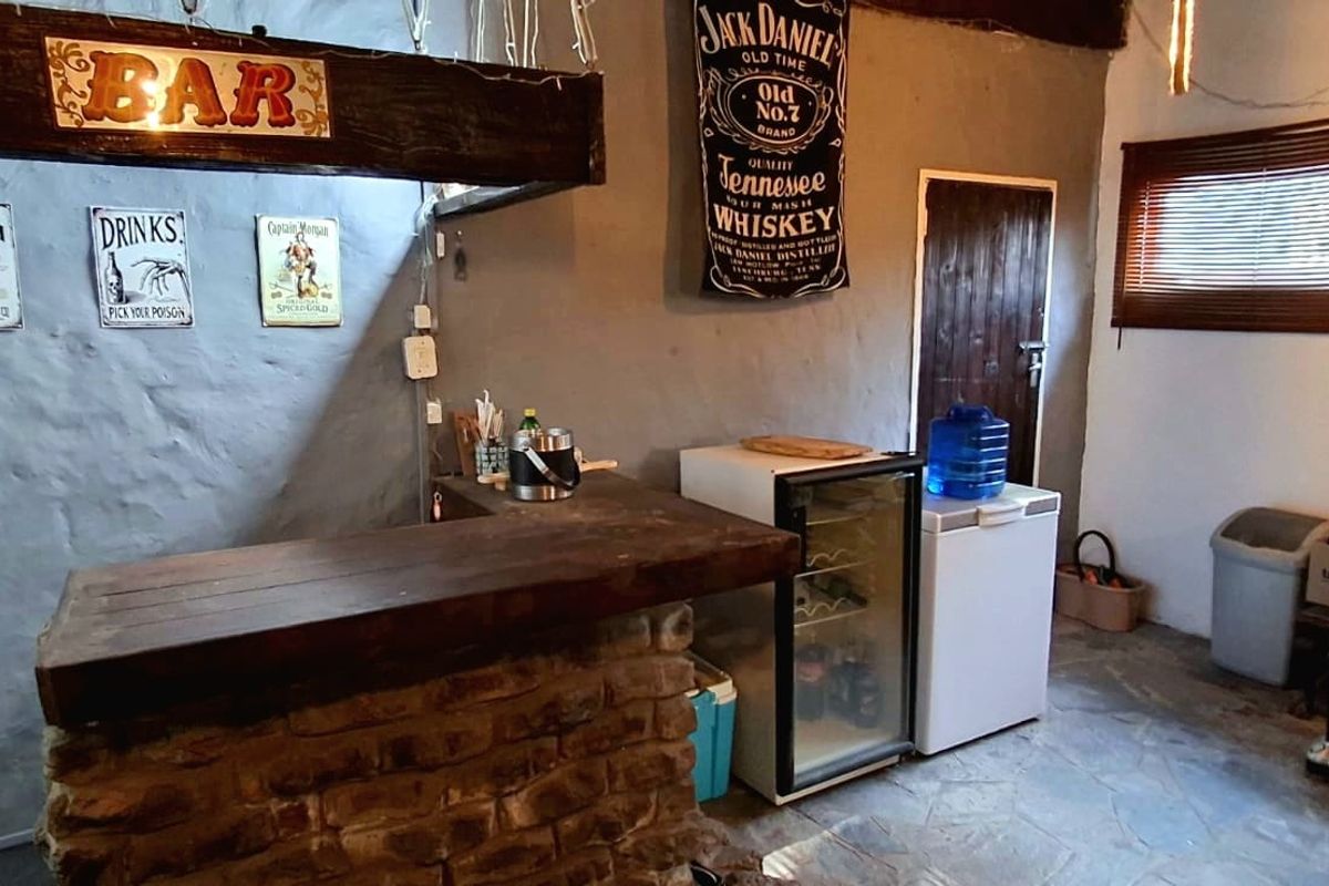 A rustic-style bar area featuring a stone-based counter, exposed timber beam, and stone flooring, offering a casual entertainment space.