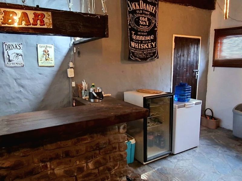 A rustic-style bar area featuring a stone-based counter, exposed timber beam, and stone flooring, offering a casual entertainment space.