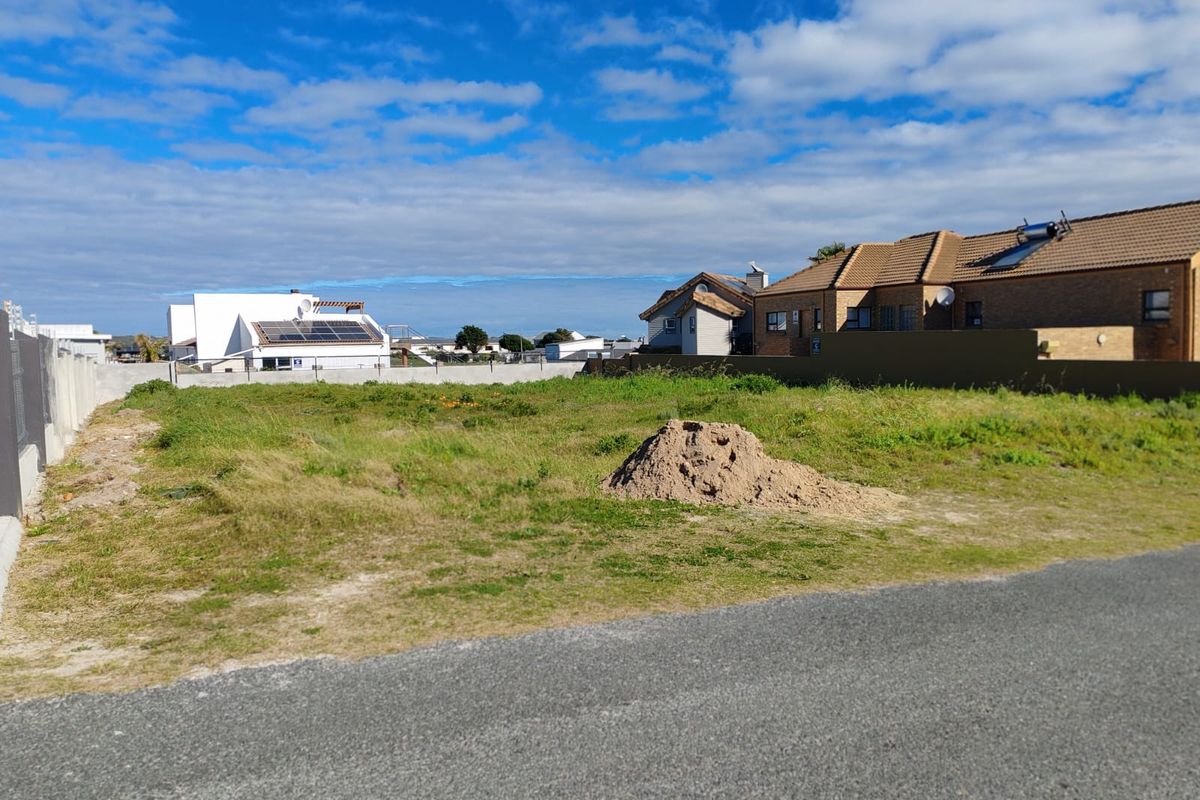 A vacant residential plot of land featuring boundary walls and direct street access, situated in a developed neighborhood.