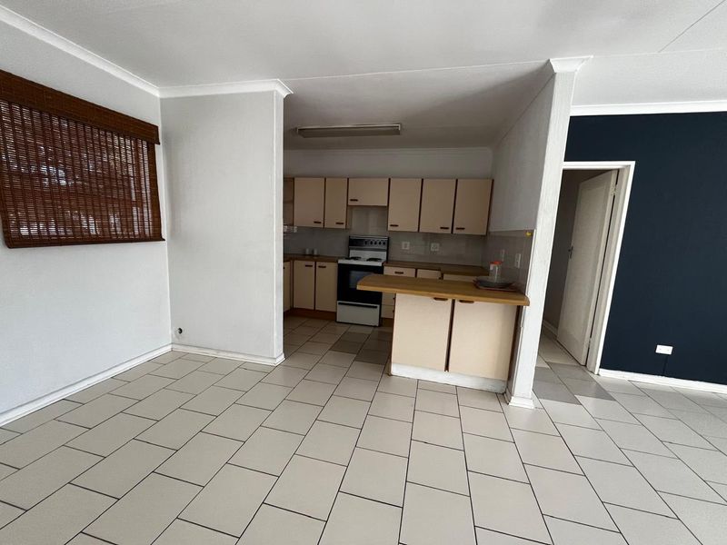 Open plan living area featuring tiled flooring and a functional kitchen with built-in cabinetry and a breakfast nook.