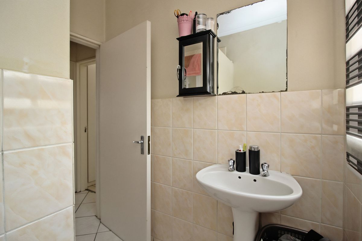A functional bathroom featuring a pedestal basin, tiled splashback, and tiled flooring, providing a clean and practical space.