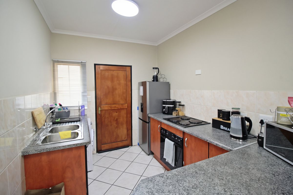 Functional kitchen featuring laminate countertops, built-in oven, electric hob, double bowl sink, and tiled splashbacks with ample storage cabinetry.
