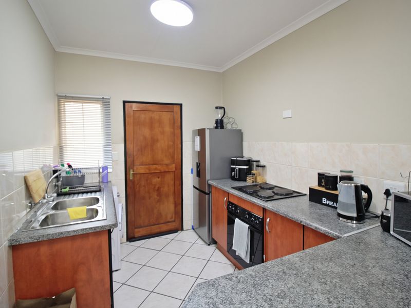 Functional kitchen featuring laminate countertops, built-in oven, electric hob, double bowl sink, and tiled splashbacks with ample storage cabinetry.