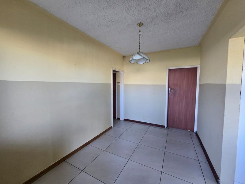 An empty hallway featuring tiled flooring and neutral two-tone wall paint, providing access to adjacent rooms.