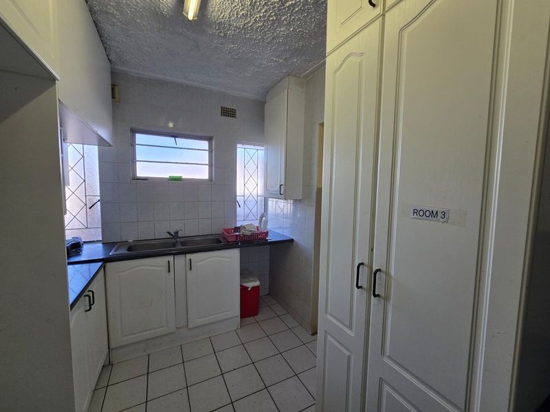 A functional scullery area featuring built-in cabinetry, a double basin sink, and tiled finishes, offering practical utility space for the townhouse.