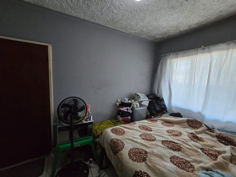 A bedroom featuring a textured ceiling and grey walls, requiring cosmetic updates to improve the overall condition and appeal of the space.