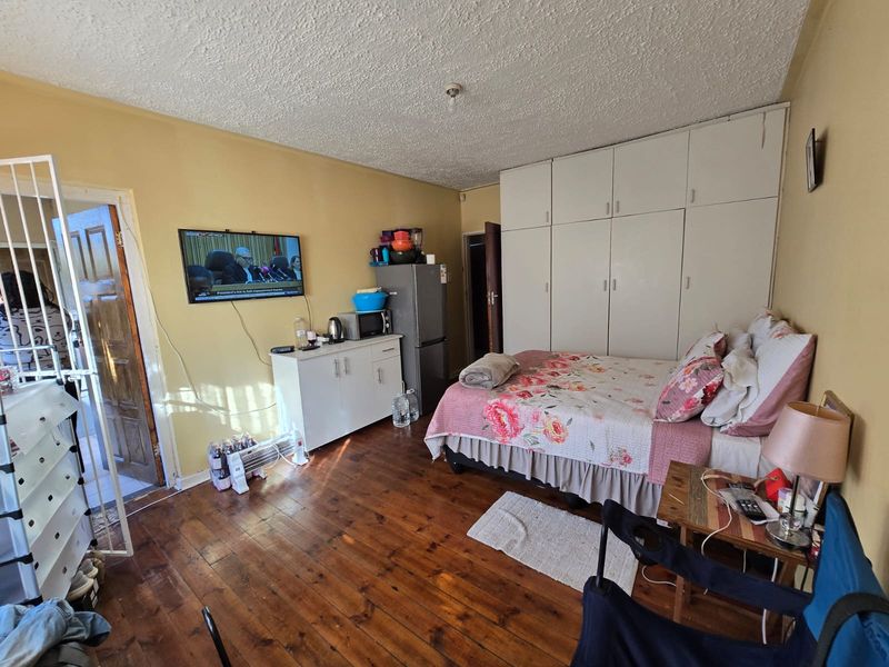 A bedroom featuring timber flooring, built-in cupboards, and a security gate at the entrance.