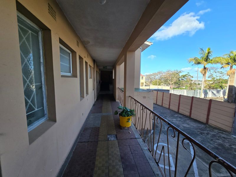 An exterior covered walkway featuring tiled flooring and a metal balustrade, providing access to the townhouse units.