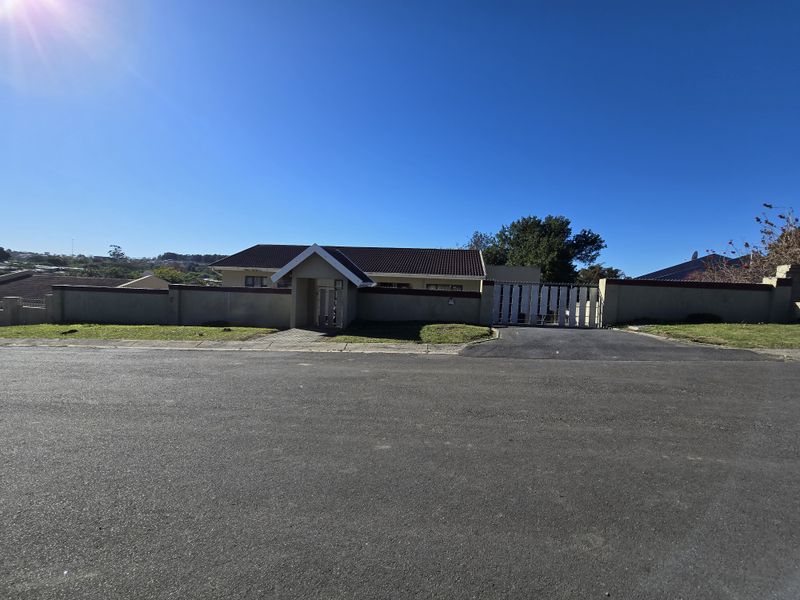 Front view of a residential property featuring a secure perimeter wall, gated entrance, and a tiled roof with a paved driveway.