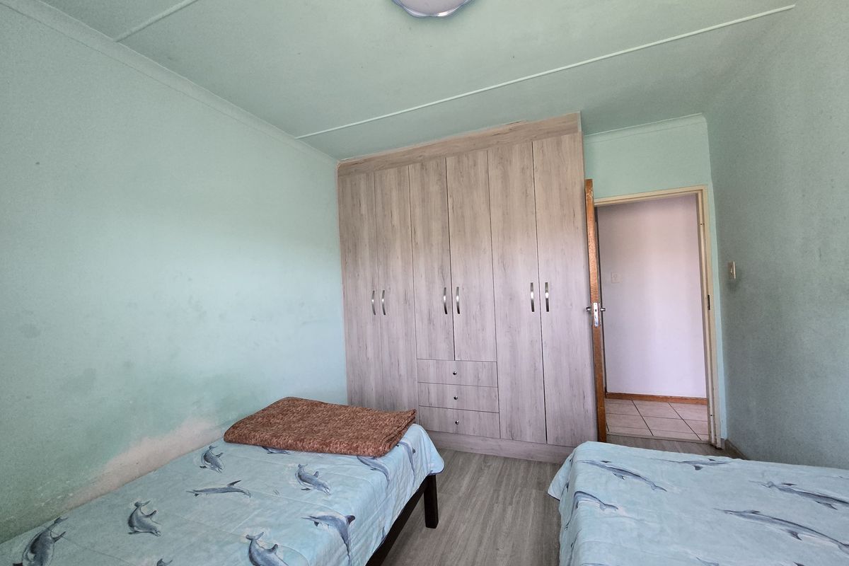 A bedroom featuring built-in cupboards and laminate flooring, requiring cosmetic attention to the walls.