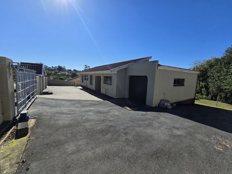 Front exterior view of the property featuring a paved and asphalt driveway, a single garage, and secure metal gate access.