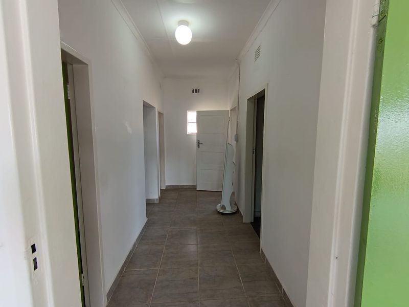 A functional hallway featuring neutral tiled flooring and white walls, providing access to multiple rooms within the home.