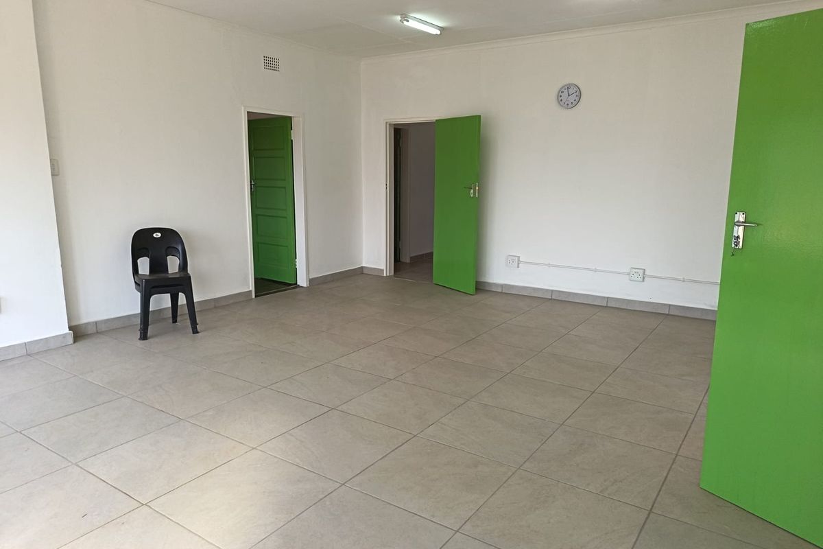An empty, neutrally painted living area featuring large format floor tiles and multiple internal access points.