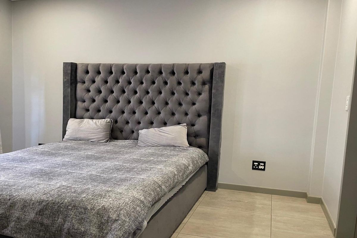 A well-maintained bedroom featuring neutral wall tones, tiled flooring, and modern electrical fixtures.