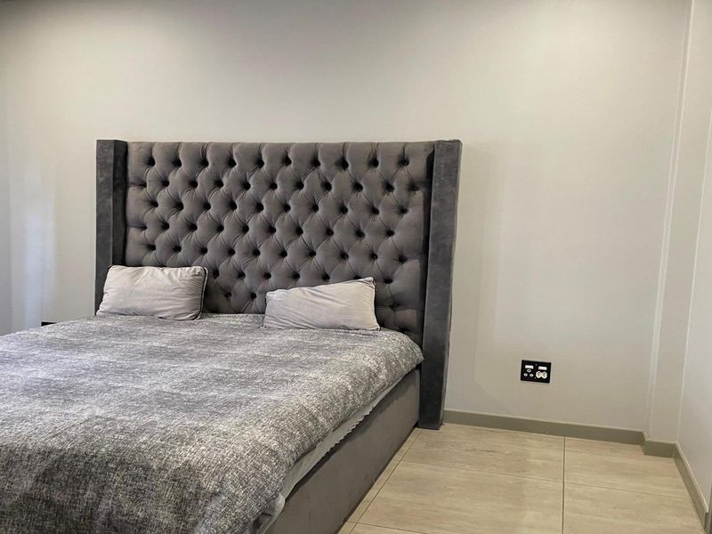 A well-maintained bedroom featuring neutral wall tones, tiled flooring, and modern electrical fixtures.