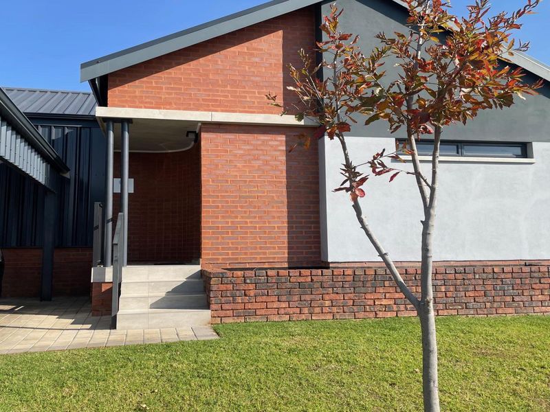Modern front facade featuring a combination of red brick and rendered walls, concrete entrance steps, and an adjacent covered carport.