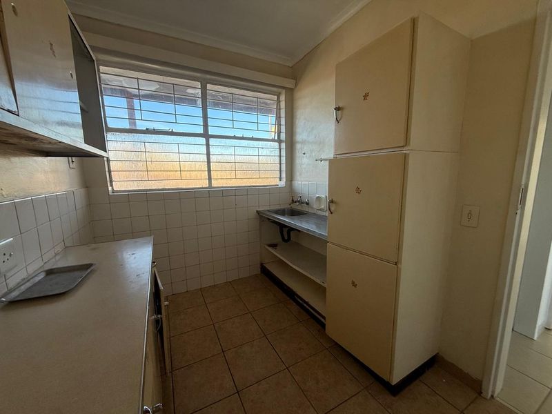 A functional scullery area featuring built-in cabinetry, a stainless steel sink, and tiled splashbacks, offering a practical space for laundry or kitchen preparation.