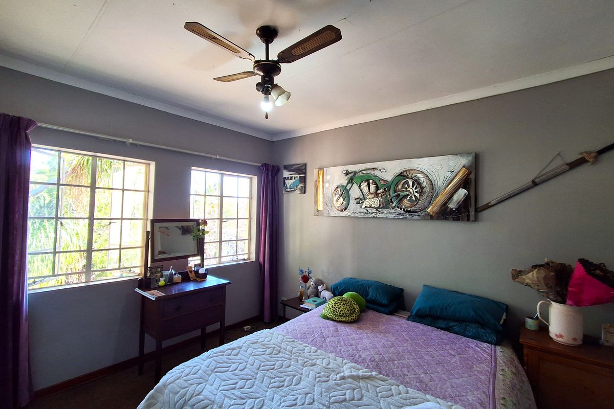 A standard bedroom featuring a ceiling fan, grid-pattern windows, and coved cornicing, with visible signs of wear on the ceiling.