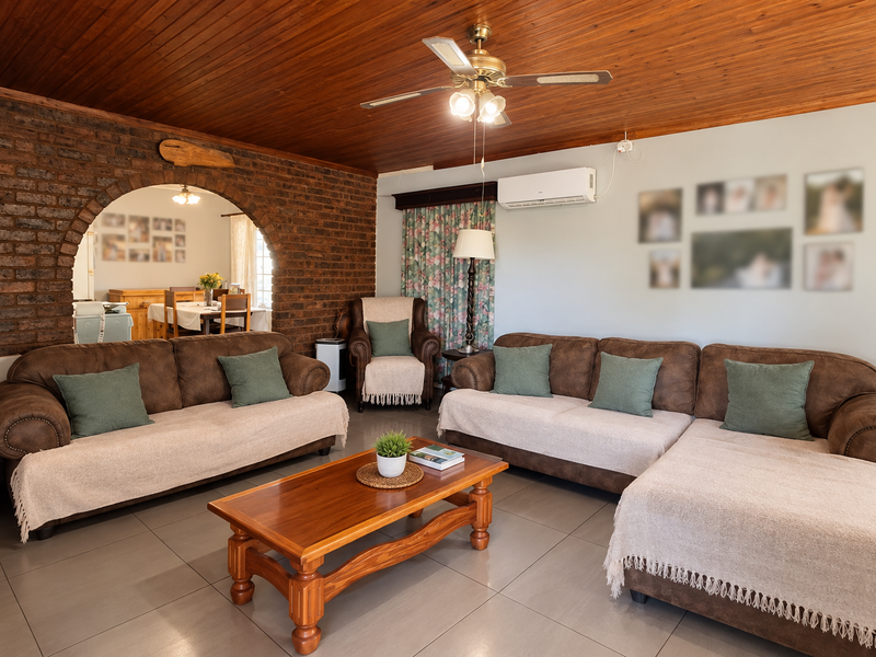 Spacious living room featuring a warm timber ceiling, exposed brick feature wall, arched entryway, and tiled flooring with integrated air conditioning.