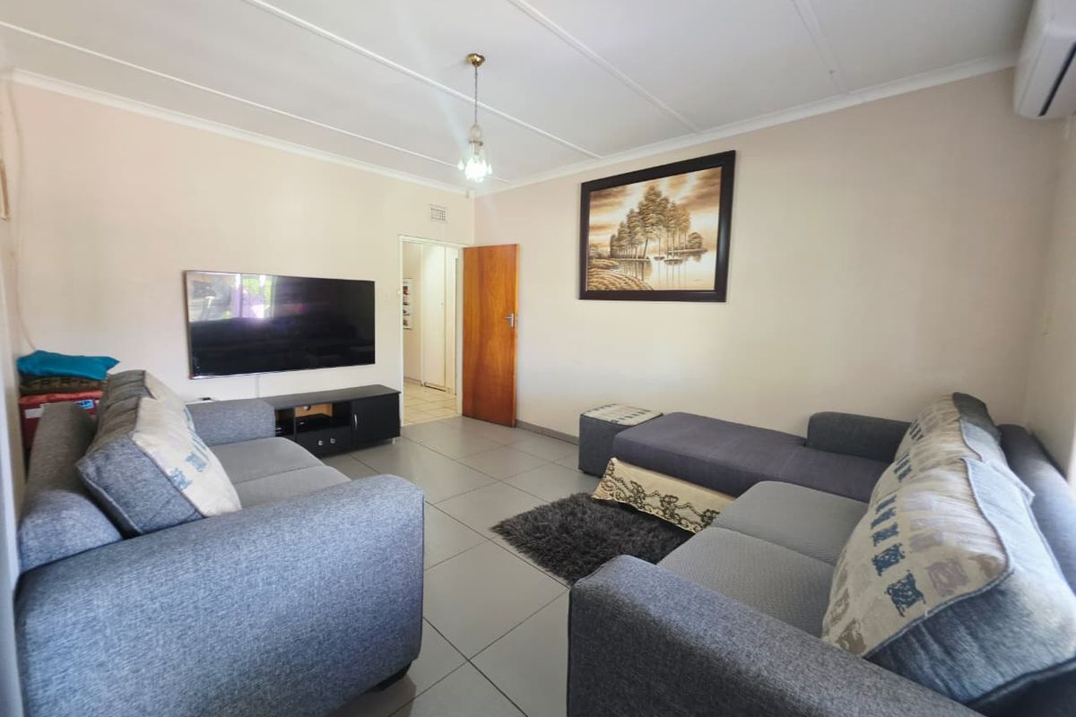 A comfortable living room featuring tiled flooring, a wall-mounted air conditioning unit, and a neutral color palette.