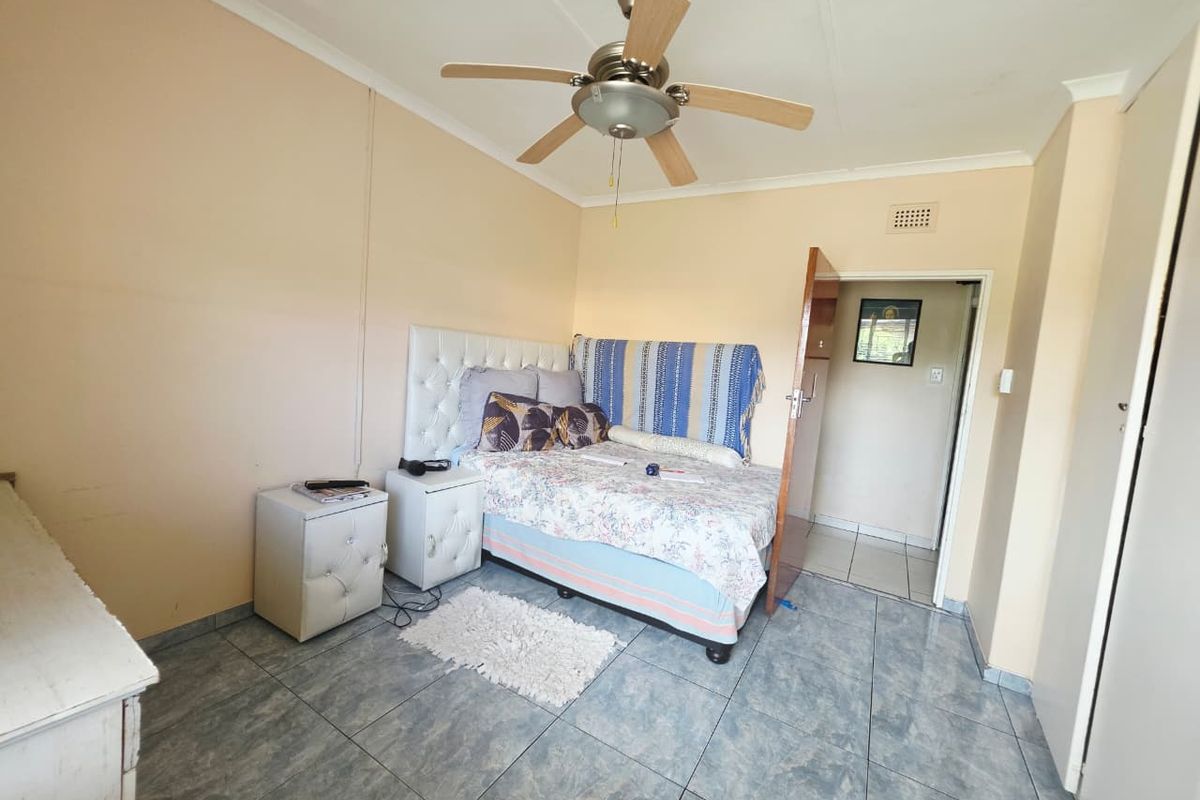 A functional bedroom featuring tiled flooring, a ceiling fan, and built-in storage space.