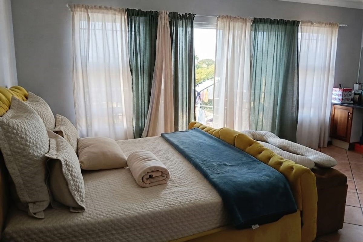 A bedroom featuring tiled flooring and a large sliding glass door providing natural light and access to the exterior.