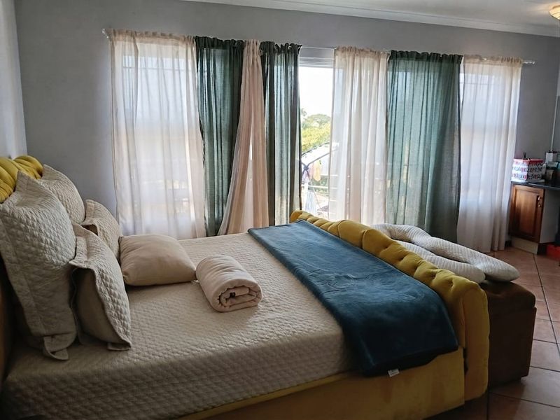 A bedroom featuring tiled flooring and a large sliding glass door providing natural light and access to the exterior.