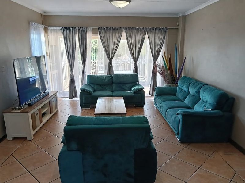 A comfortable living room featuring ceramic floor tiles and large sliding glass doors that provide natural light and access to the outdoor area.