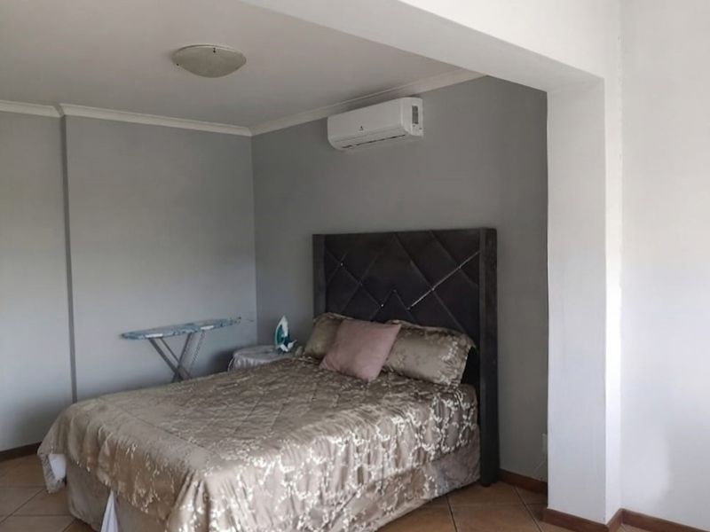 A bedroom featuring tiled flooring and a wall-mounted split-system air conditioning unit.