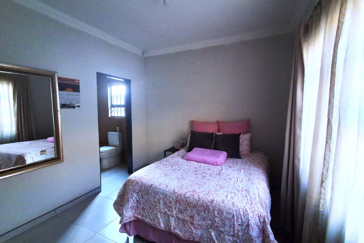 A bedroom featuring tiled flooring and coved ceilings, with an adjoining en-suite bathroom visible through the doorway.