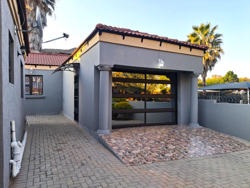 A well-maintained single garage featuring a modern sectional door, decorative columns, and a paved driveway with a tiled apron.