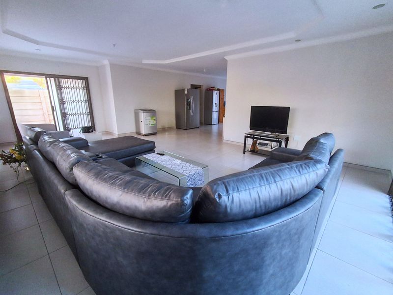 Spacious open-plan living area featuring tiled flooring, a recessed ceiling, and a sliding glass door leading to the exterior.