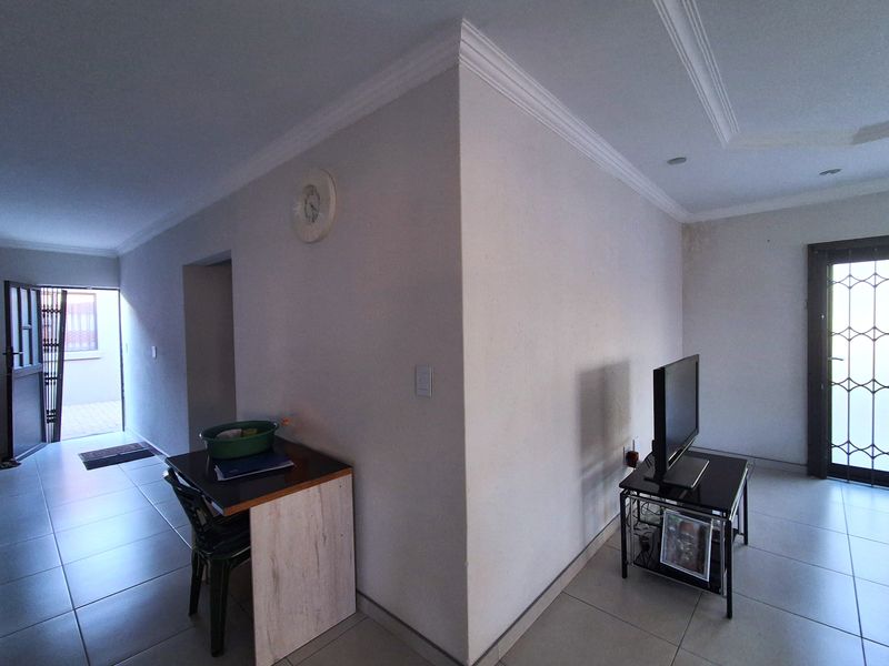 Living area featuring tiled flooring, decorative cornicing, and access to exterior spaces via security gates. Visible water staining on the wall requires attention.