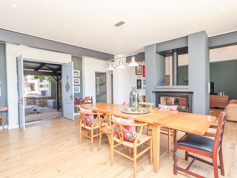 Spacious open-plan dining area featuring a modern built-in fireplace, wood-look tile flooring, and direct access to an outdoor patio through double doors.