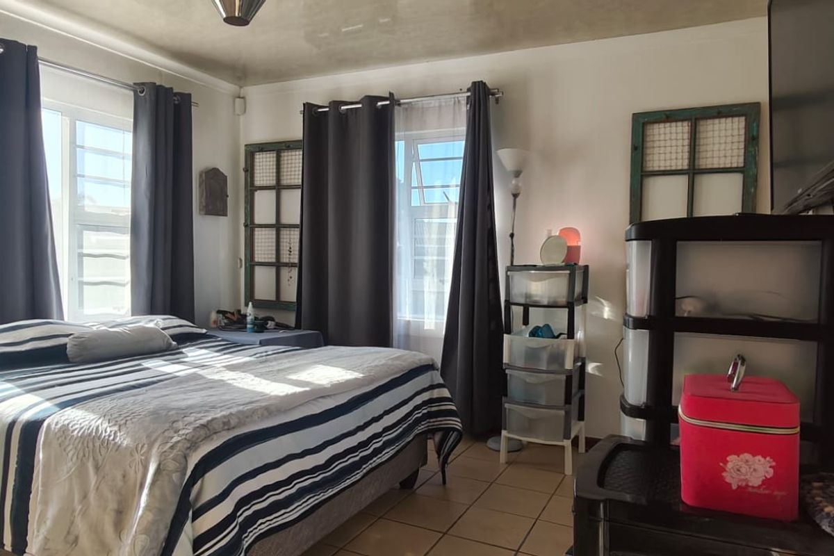 A bedroom featuring tiled flooring and large windows that provide ample natural light.