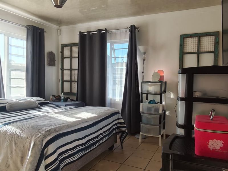 A bedroom featuring tiled flooring and large windows that provide ample natural light.