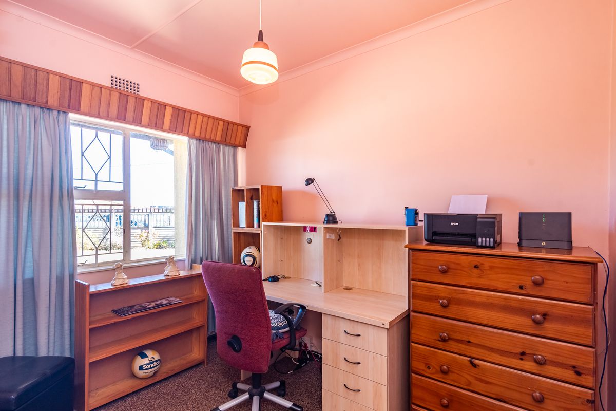 A functional bedroom featuring carpet flooring, a timber window pelmet, and security bars on the window.