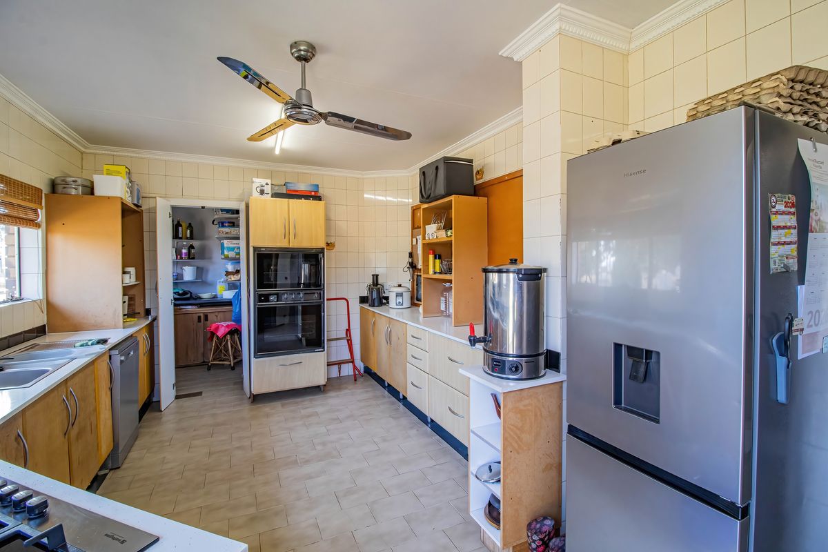 Functional kitchen featuring built-in oven, ample cabinetry, tiled walls, and direct access to a scullery area.