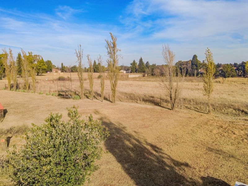 An aerial view of the expansive small holding grounds, featuring open fields, mature trees, and perimeter fencing.