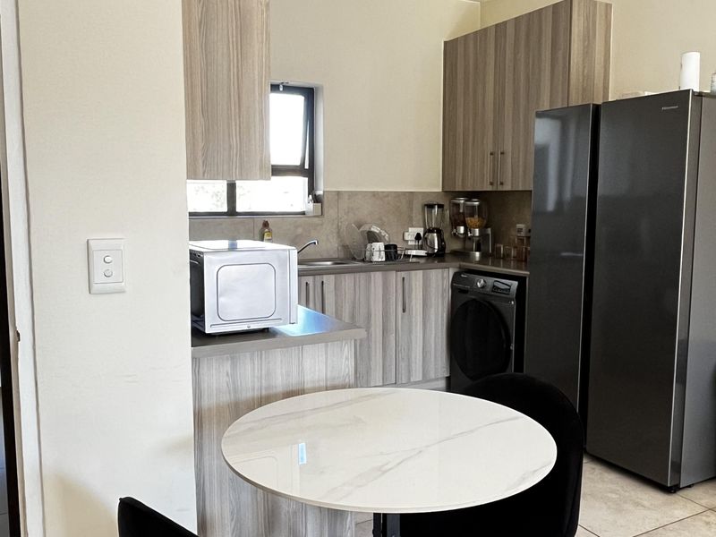 A functional kitchen featuring modern wood-look cabinetry, tiled flooring, and integrated space for appliances, offering a clean and practical layout.