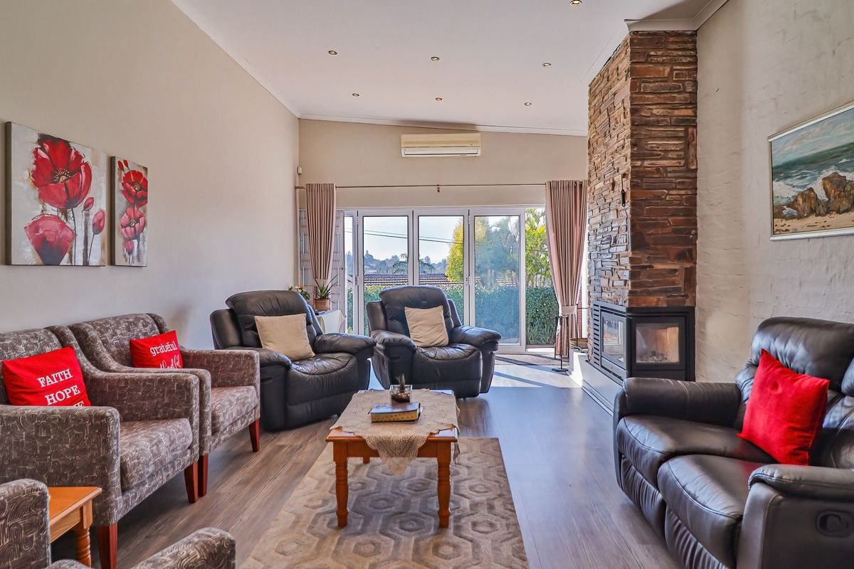 Spacious living room featuring a prominent stone-clad fireplace, laminate flooring, recessed lighting, and direct access to the outdoor area through sliding glass doors.