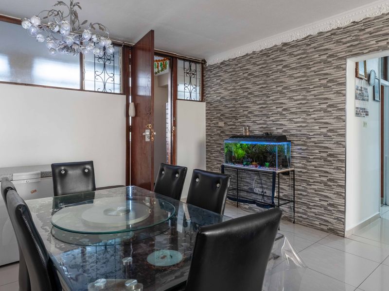 Dining room featuring a stone-effect feature wall, decorative ceiling cornice, and tiled flooring, providing a functional space for meals.