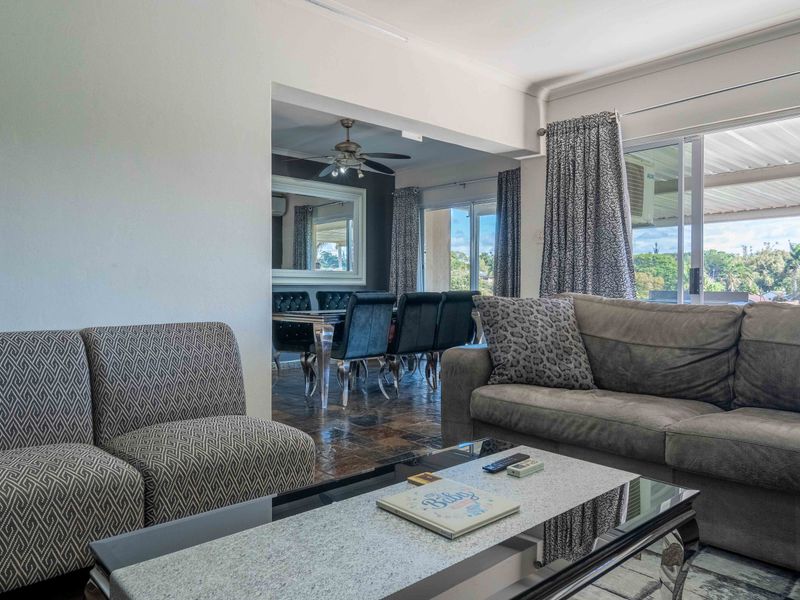 Open plan living and dining area featuring tiled flooring, ceiling fan, and sliding glass doors leading to an outdoor space.