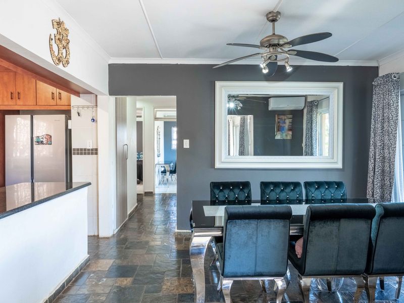 Open-plan dining area featuring slate tile flooring, a ceiling fan, and a breakfast bar connecting to the kitchen space.