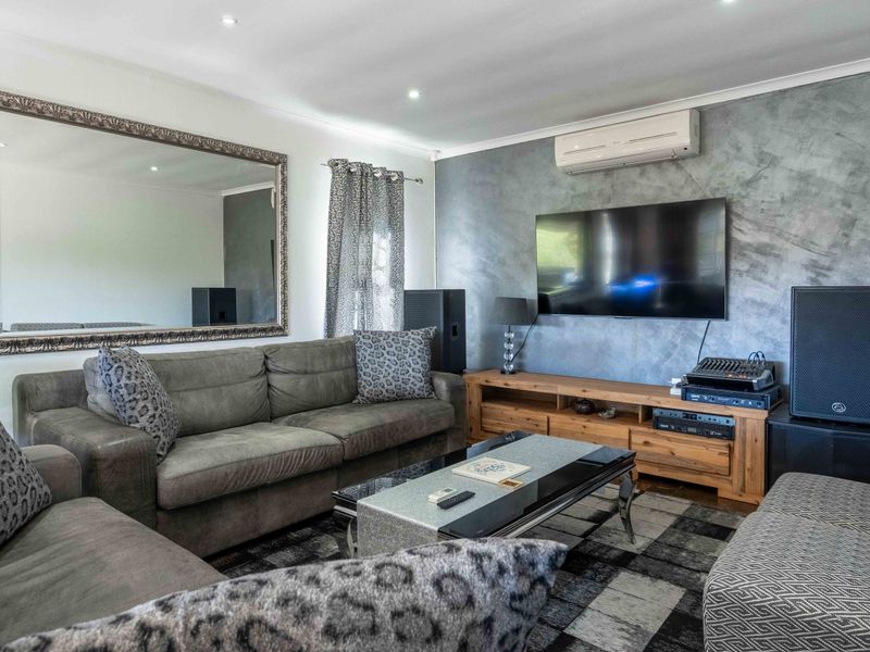 A comfortable living room featuring a textured feature wall, split-system air conditioning, and recessed downlighting.