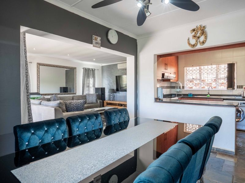 Open-plan living and dining area featuring a connected kitchen with built-in cabinetry, tiled splashbacks, and integrated laundry facilities.